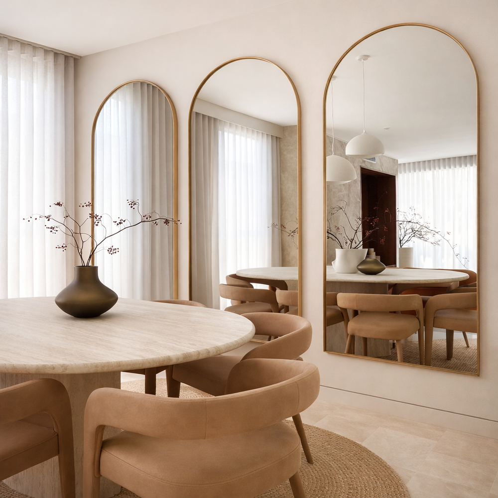 Dining room with round table, chairs, and large mirrors on the wall.