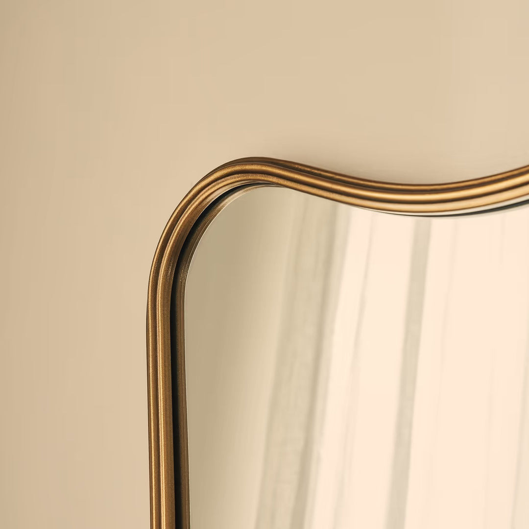 Gold-framed mirror on a beige wall