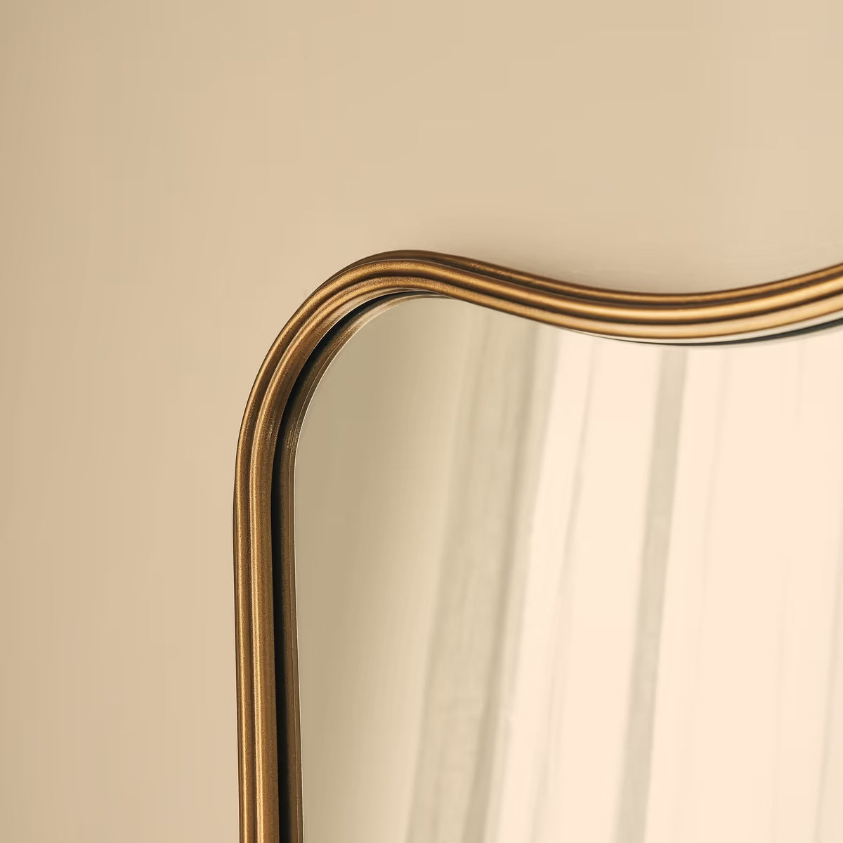 Gold-framed mirror on a beige wall