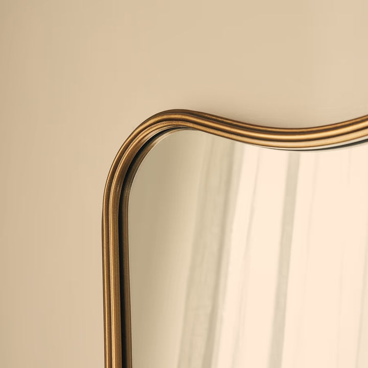 Gold-framed mirror on a beige wall