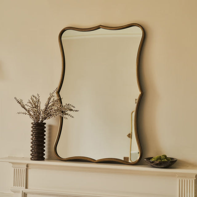 Decorative mirror on a mantelpiece with a vase and small bowl.